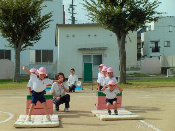 園庭で巧技台からジャンプする園児たちの様子