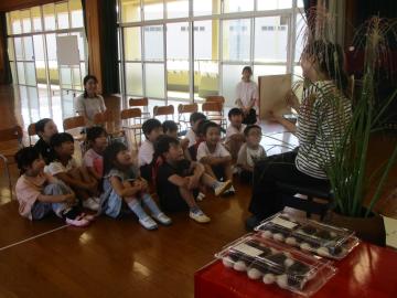 遊戯室でお月見の紙芝居を見る園児たちの様子