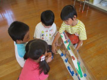 室内でどんぐりを転がす道を作る園児たちの様子