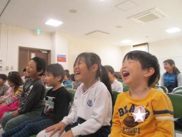 室内で腹話術を見て口を開けて笑う園児たちの様子