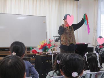 室内で箱からカラフルな布を出すマジックを披露する男性の様子