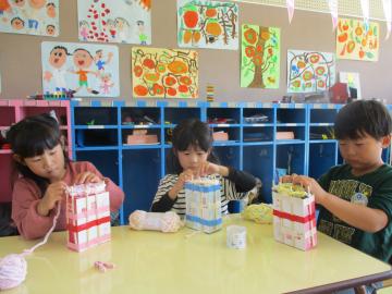 室内で毛糸を使って編み物をする園児たちの様子