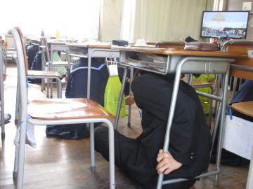 机の下に避難する生徒の様子