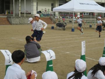 高学年の児童がトラック上で徒競走のゴールをする様子