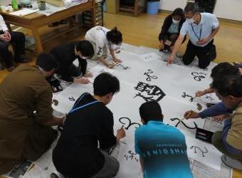 先生の「和」の字を中心にみんなで古代文字を寄せ書きをする