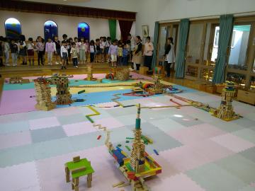 室内でみんなでできあがった積木を見ている園児たちの様子