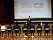 体育館で椅子に座った生徒が講習を受ける様子