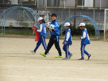 校庭でボールやコーンを持ち歩く児童たちと選手の様子