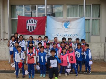 校舎前で選手と記念写真を撮る児童たちの様子