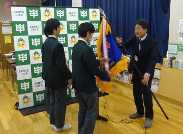 表彰伝達で旗を受け取る生徒の様子