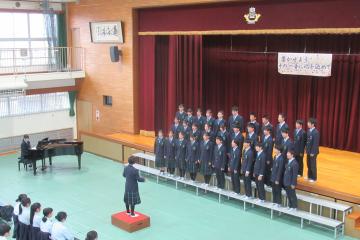 体育館の壇上で、9年2組が合唱をしている様子