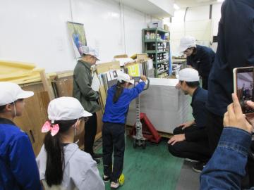 太田紙器工業の建物内で大きな荷物を運んでいる児童の様子