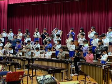 体育館の壇上で、3年生がリコーダーを演奏している様子