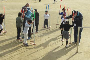 校庭で児童が竹馬に挑戦している様子