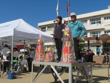 自治会対抗リレーのスターターが朝礼台に立つ様子