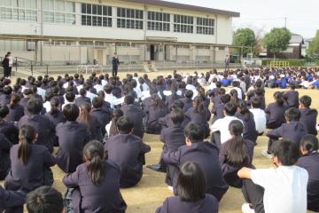 校庭で児童生徒が警察の方からの講評を聞いている様子