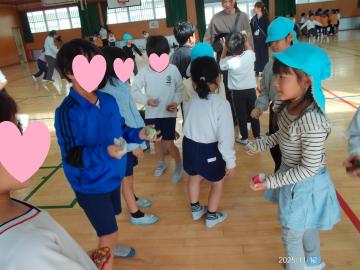 体育館内で小学生と一緒にお手玉する園児たちの様子