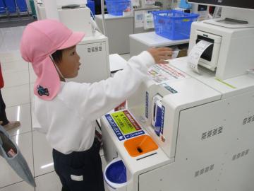 店内のセルフレジの機械から出たレシートを取ろうとする園児たちの様子