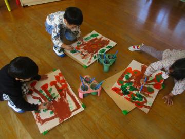 室内で柿の実や葉を絵の具で描く園児たちの様子