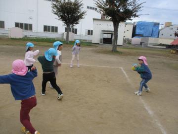 グラウンド内で中当てで友達をねらってボールを投げようとしている園児たちの様子