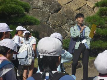 姫路城の石垣のそばで、研究員の方から説明を受ける児童の様子