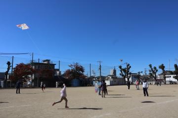 運動場で凧を上げている児童たち