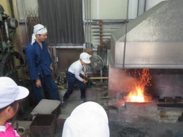 ふいごで空気を送る体験をする4年生の様子