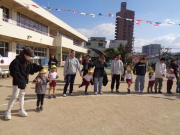 運動場で輪になって親子ダンスをしている様子