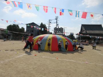 運動場で児童たちがパラバルーン演技をしています。