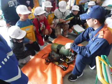 消防士さんから設備の説明を受ける児童たちの様子