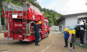 消防士さんから消防車の説明を聞く園児