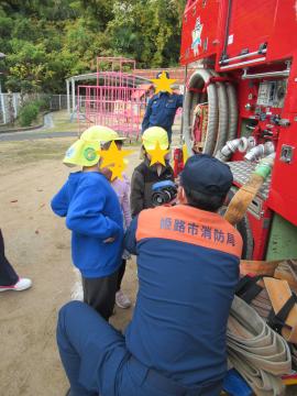 消防車についているホースについて消防士さんから説明を聞く園児