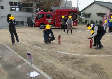 水の入った消火器で消火訓練をする園児と保護者（1）