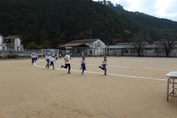 運動場を走る児童と職員