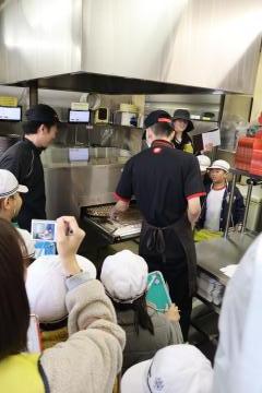 店員がピザを焼いているところを見学する児童たちです