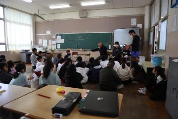 教室の床に児童が座って大上さんのお話を聞いています