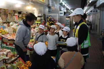 果物屋さんで児童たちが店員に質問しています