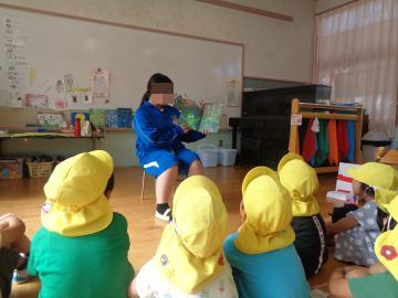 中学生のお姉さんが幼稚園児に絵本の読み聞かせをしている