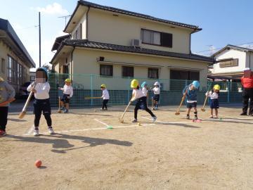 園児が園庭で老人クラブの方と一緒にグラウンドゴルフをしている