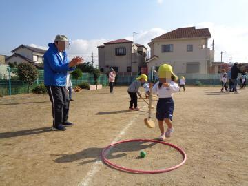 グラウンドゴルフでボールがゴールに入り、園児が老人クラブの方に拍手をしてもらっている