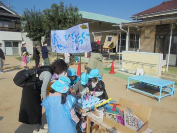 園庭で園児たちがいろいろな道具を販売している様子