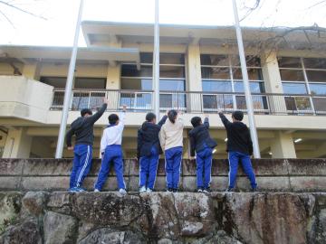 自然学校の建物の前で5年生が楽しそうに集合写真を撮っている様子