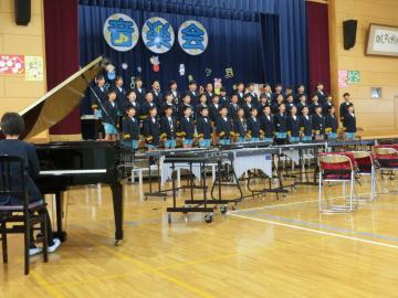 4年生が体育館の壇上で整列して合奏している