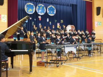 1年生が体育館の壇上に整列して楽器の合奏をしている