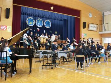 5年生が体育館の壇上とその前に整列して楽器の合奏している