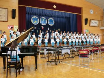6年生が体育館の壇上に整列して合唱をしている