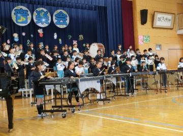 2年生が体育館の壇上とその前に整列し楽器の合奏をしている
