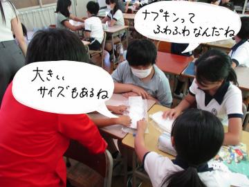ナプキンを前に話し合っている様子。写真の中に「ナプキンってふわふわなんだね」「大きいサイズもあるね」という吹き出しがあります。