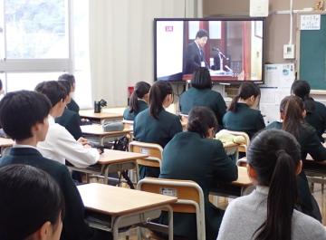 教室内のモニターで終業式での校長先生のお話を教室で聞いている2年生の様子