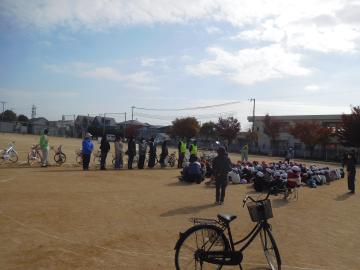 運動場で話を聞いている子どもの様子。手前に自転車があります。